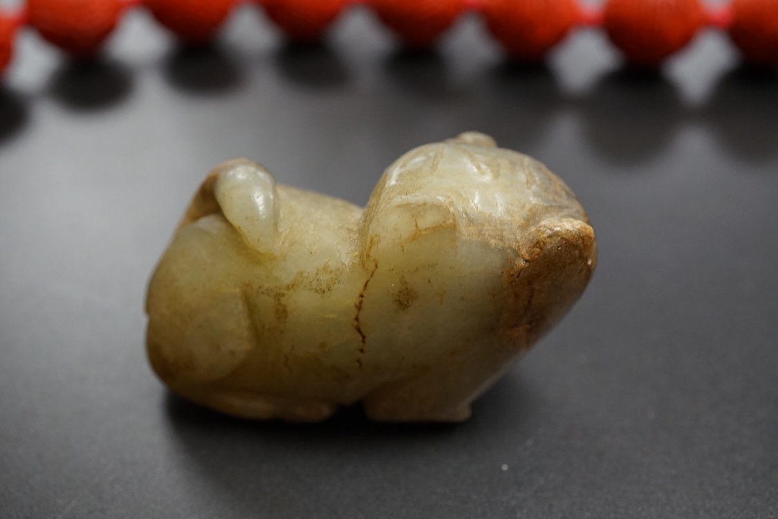 A Chinese red lacquered bead necklace and a bowenite jade figure of a cat
